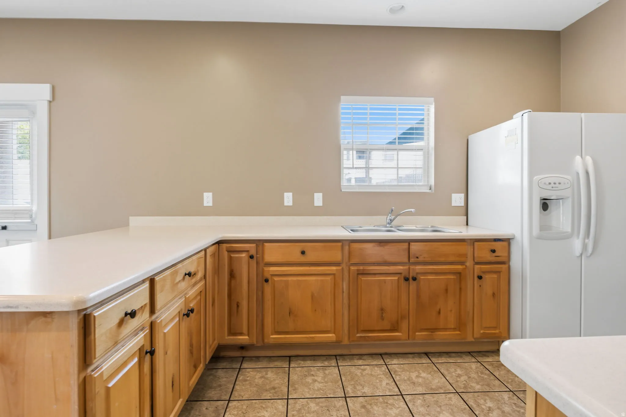 Kitchen featuring wood-finish cabinetry, light-toned countertops, and tile flooring
