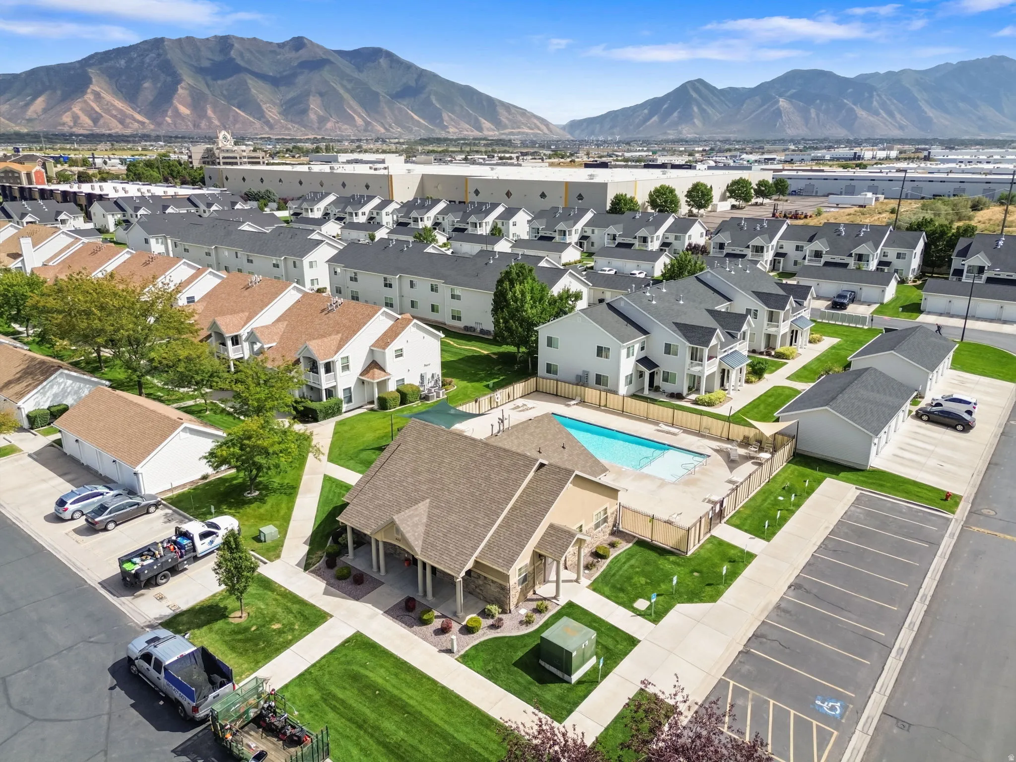 Mountain backdrop, residential development, community pool, paved parking, and manicured green spaces