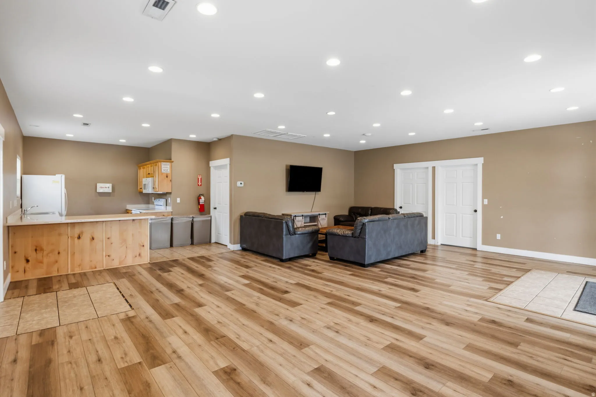 Spacious open-concept living area featuring wood-finish flooring throughout, recessed ceiling lighting, and comfortable seating arrangement