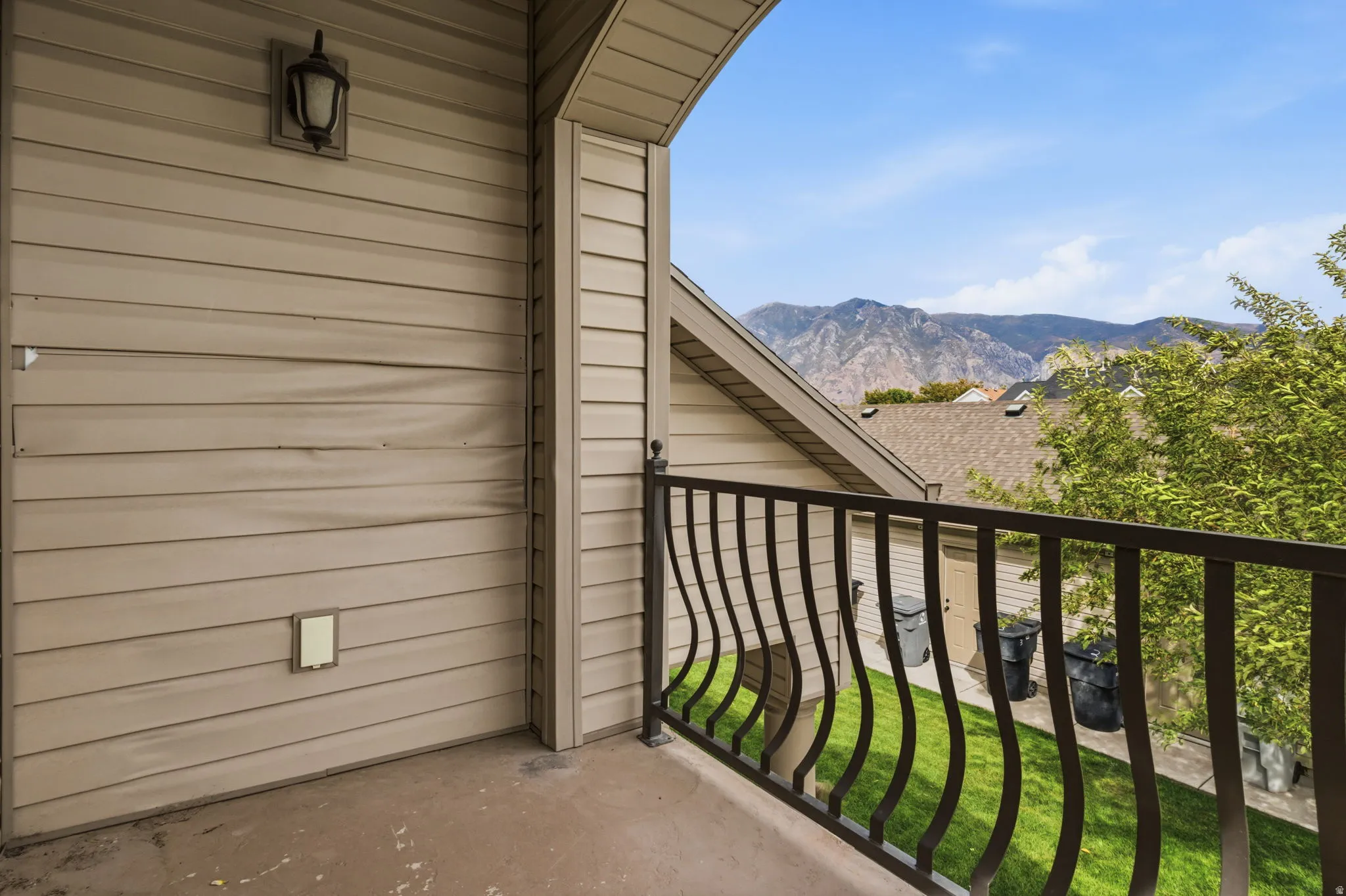 Balcony featuring metal railings, exterior wall sconce, and mountain backdrop