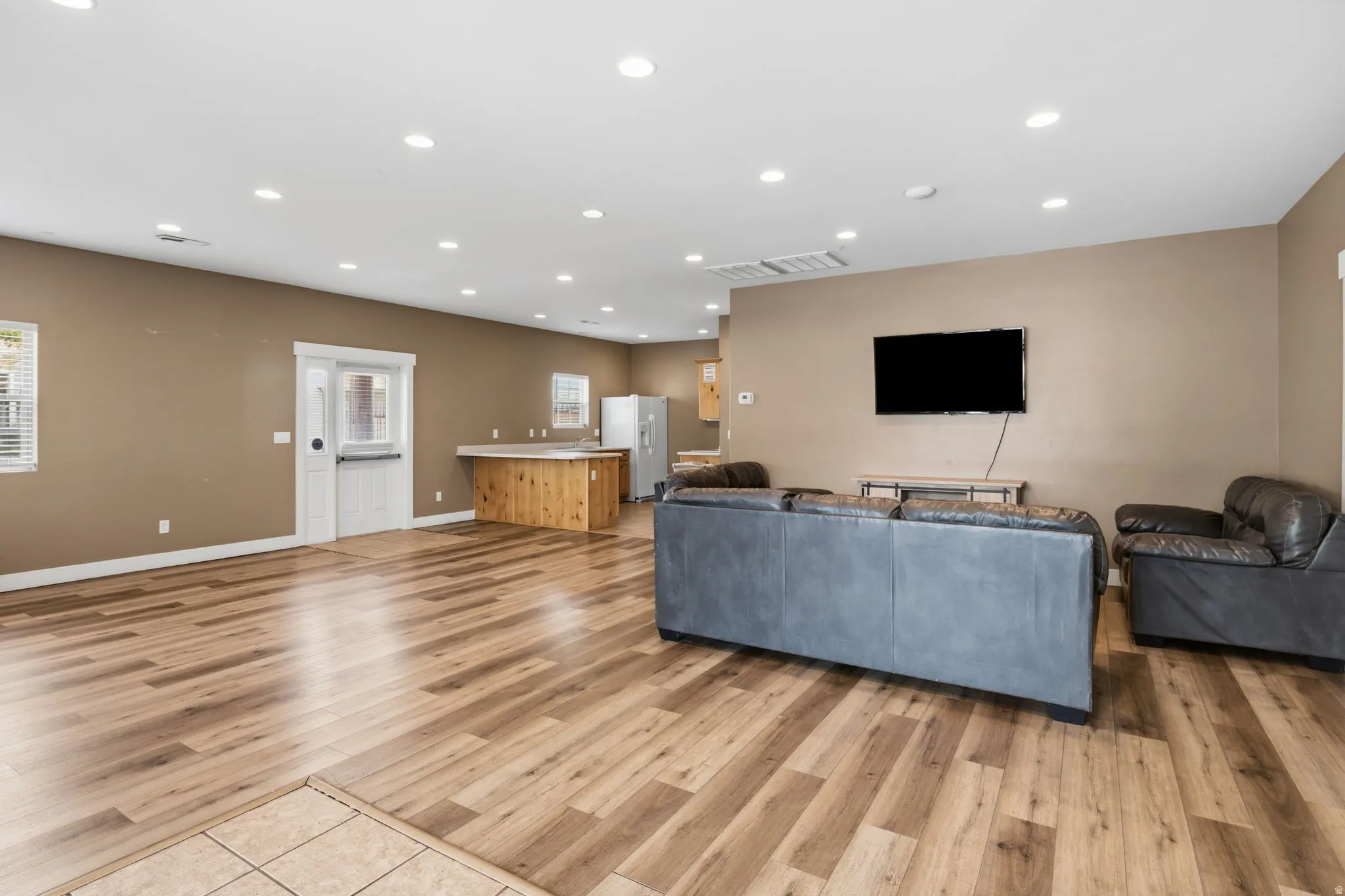 Spacious open-concept interior featuring wood-finish flooring, recessed lighting, and a built-in wood-paneled breakfast bar