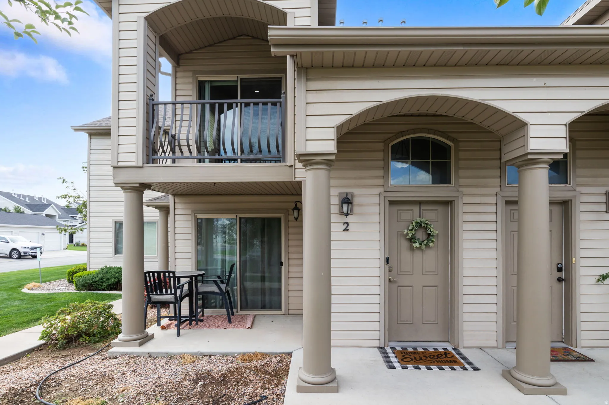 Tan horizontal siding with arched entryway features, and a private upper balcony