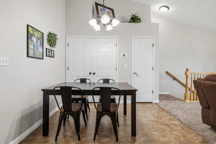 Vaulted ceiling with an overhead light fixture, wood-finish flooring, and white paneled doors