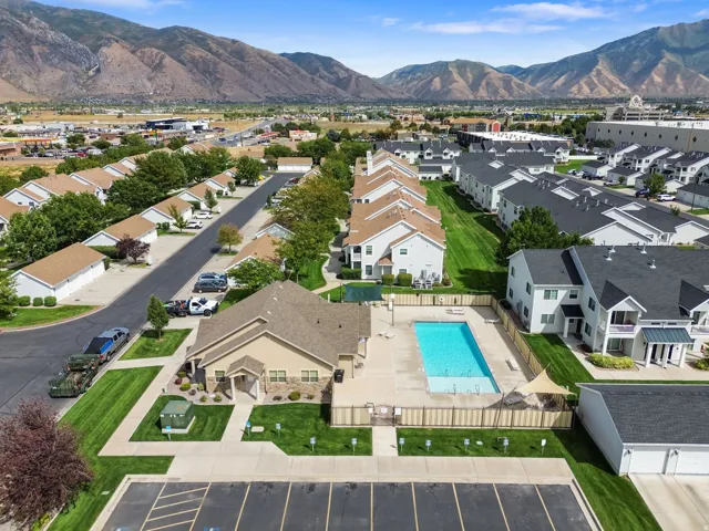 Community pool area with surrounding fencing, adjacent multi-story residences, and distant mountainous terrain