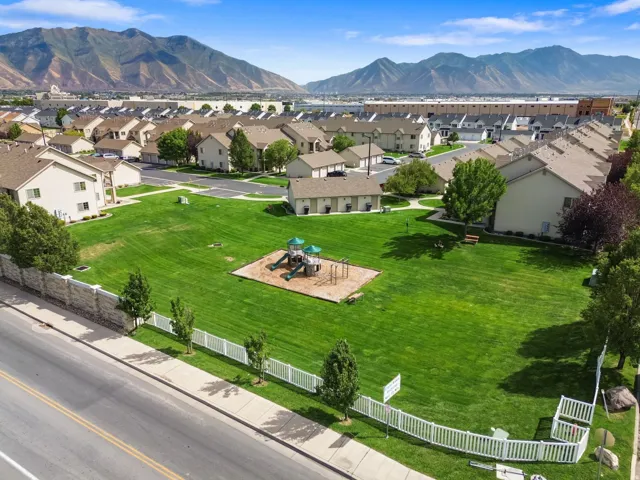 Expansive green space featuring a playground structure and surrounding residential properties