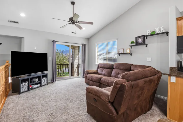 Vaulted ceiling, ceiling fan, recessed lighting, sliding glass door, and built-in shelving