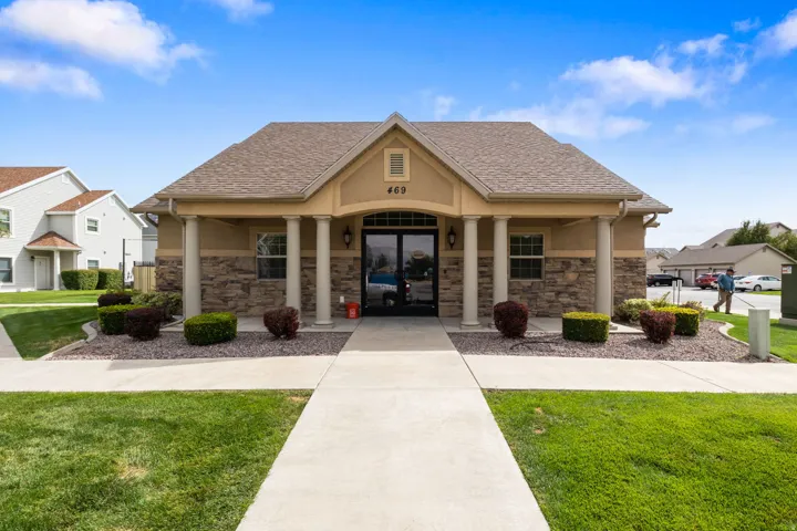 Building facade with stone accents, stucco finish, a covered entry, and decorative pillars