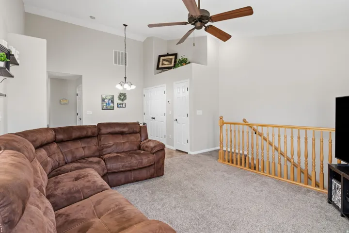 Vaulted ceilings with crown molding, ceiling fan, and carpeted flooring