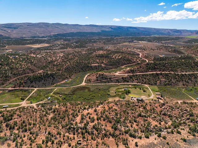 Expansive rural landscape featuring winding unpaved roads, natural terrain, and distant mountain ranges