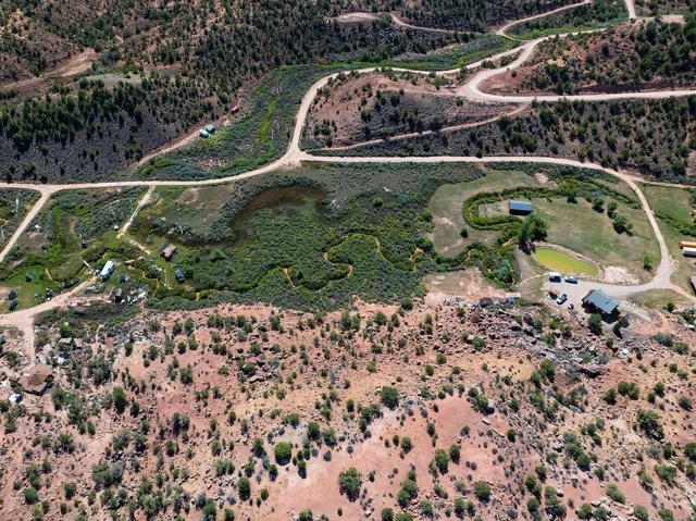 Expansive property featuring varied terrain, multiple structures, established roadways, and natural water features
