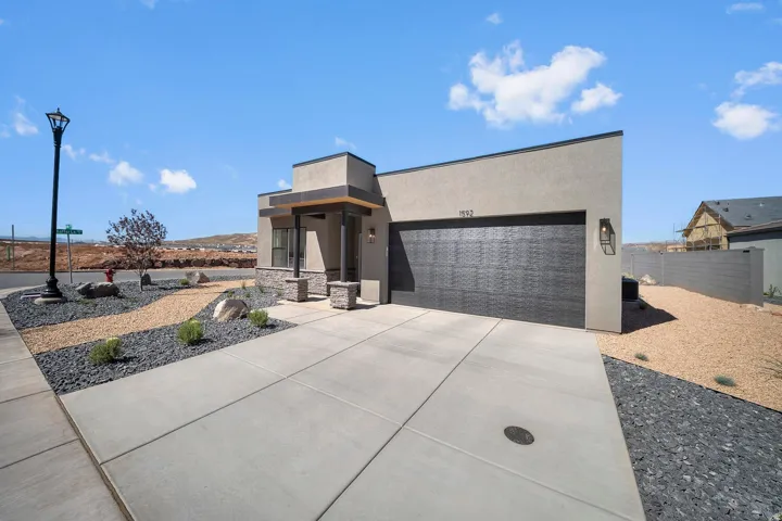Modern stucco exterior with a textured garage door, stone accents, and a covered entry