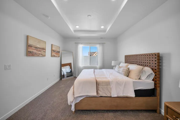 Tray ceiling with recessed lighting, wall-to-wall carpeting, and a window with white blinds