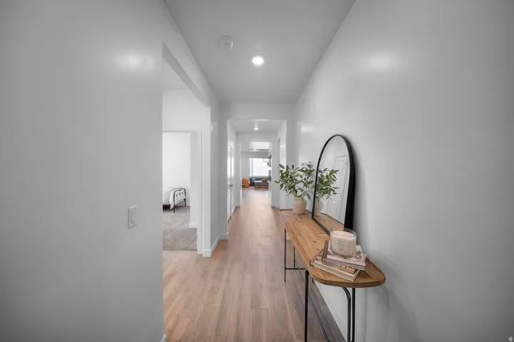 Recessed lighting illuminates wood-finish flooring in this hallway