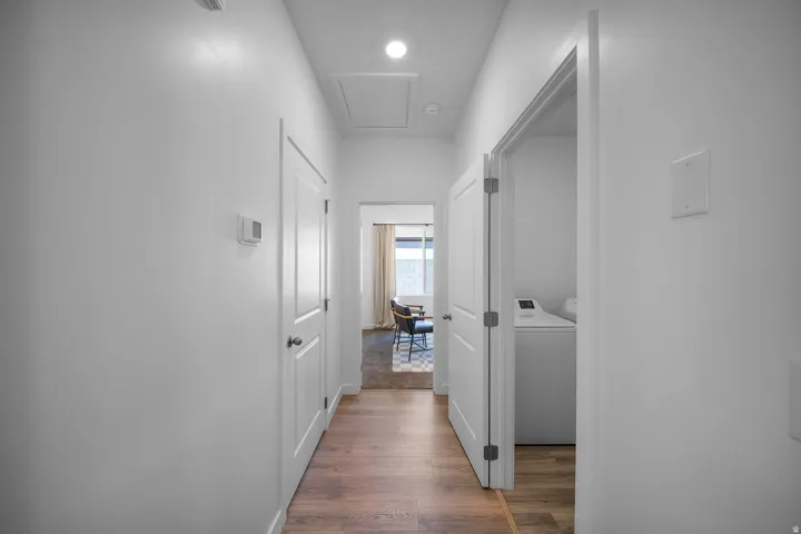 Hallway with wood-finish flooring, recessed lighting, and white paneled doors