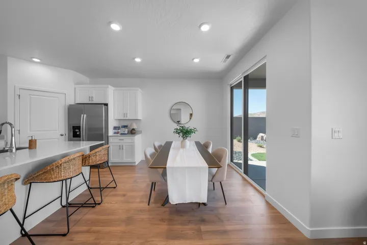 Wood-finish flooring, white cabinetry, stainless steel refrigerator, white quartz countertops, and a full-height sliding glass door