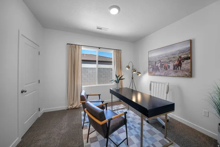 White painted walls, neutral carpet flooring, recessed ceiling light, and a window with a black frame