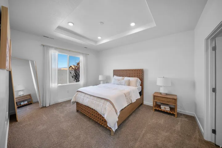 Tray ceiling with recessed lighting, carpeted flooring, and a large window