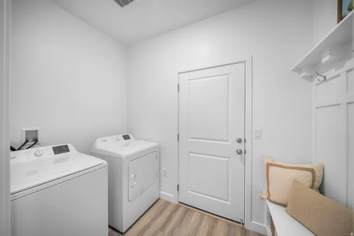 Wood-finish flooring, white paneled door, and built-in hall tree with hooks