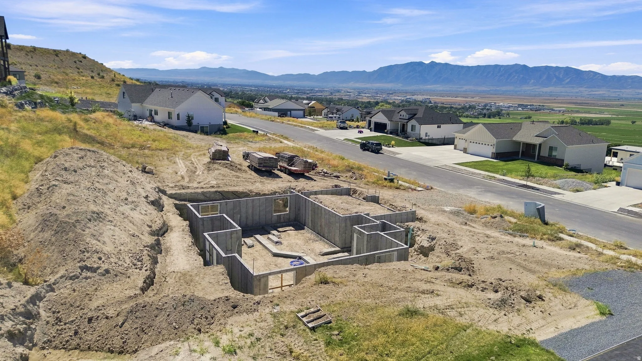 Hillside lot featuring a foundation for new construction, established neighborhood, and distant mountain range