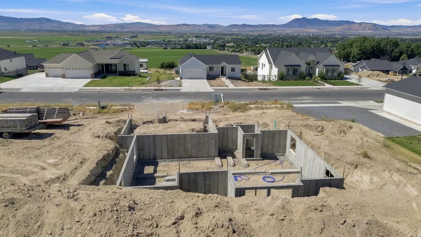 Concrete foundation with excavated earth, surrounded by developed residential properties, with distant mountains