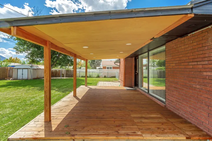 Newly Rebuilt expansive wooden deck with an integrated overhead covering, and recessed lighting,