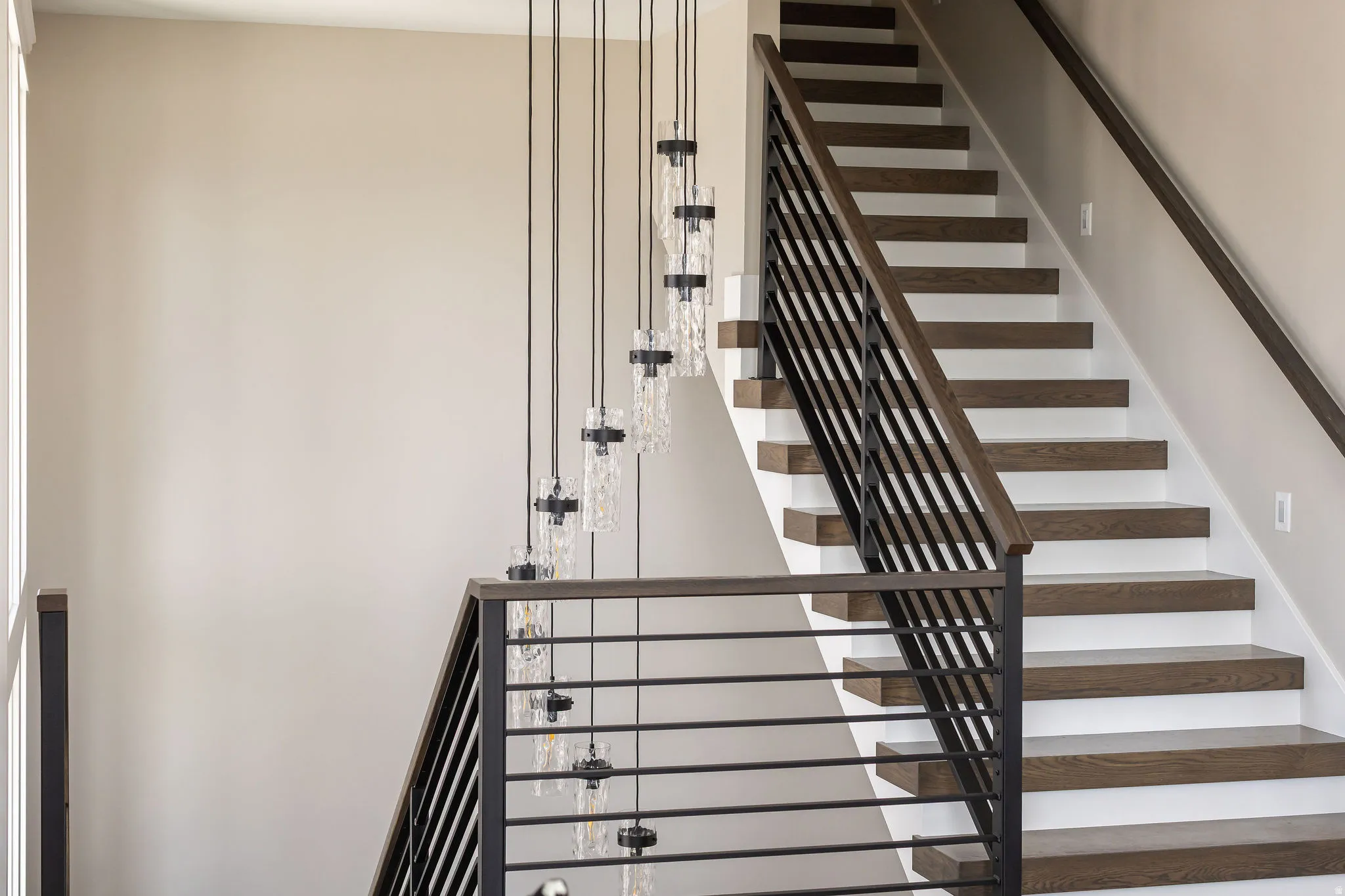 Staircase featuring wood treads, white risers, and a contemporary metal railing