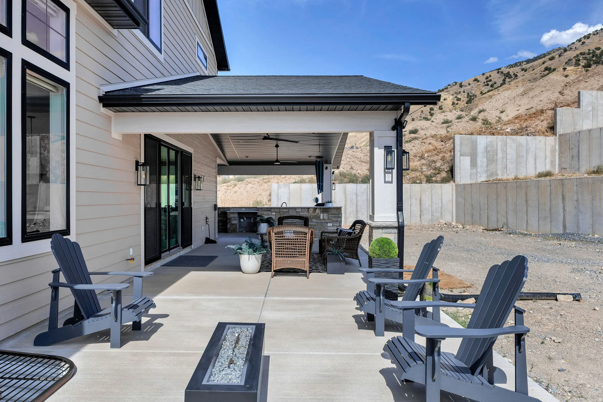Covered patio featuring a built-in outdoor kitchen, ceiling fan, and concrete flooring