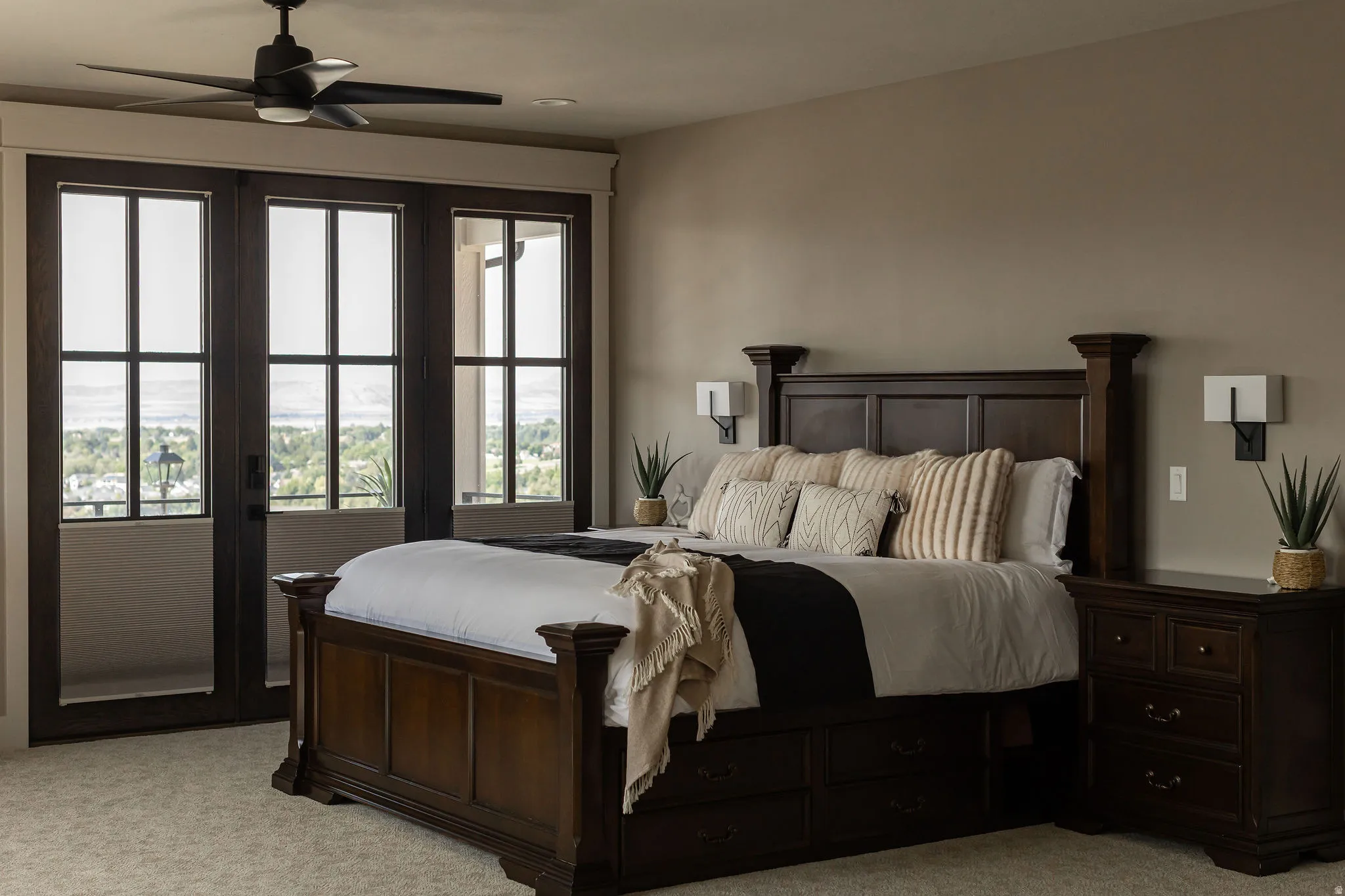 Three-panel glass doors, ceiling fan with integrated lighting, recessed lighting, and wall-mounted sconces