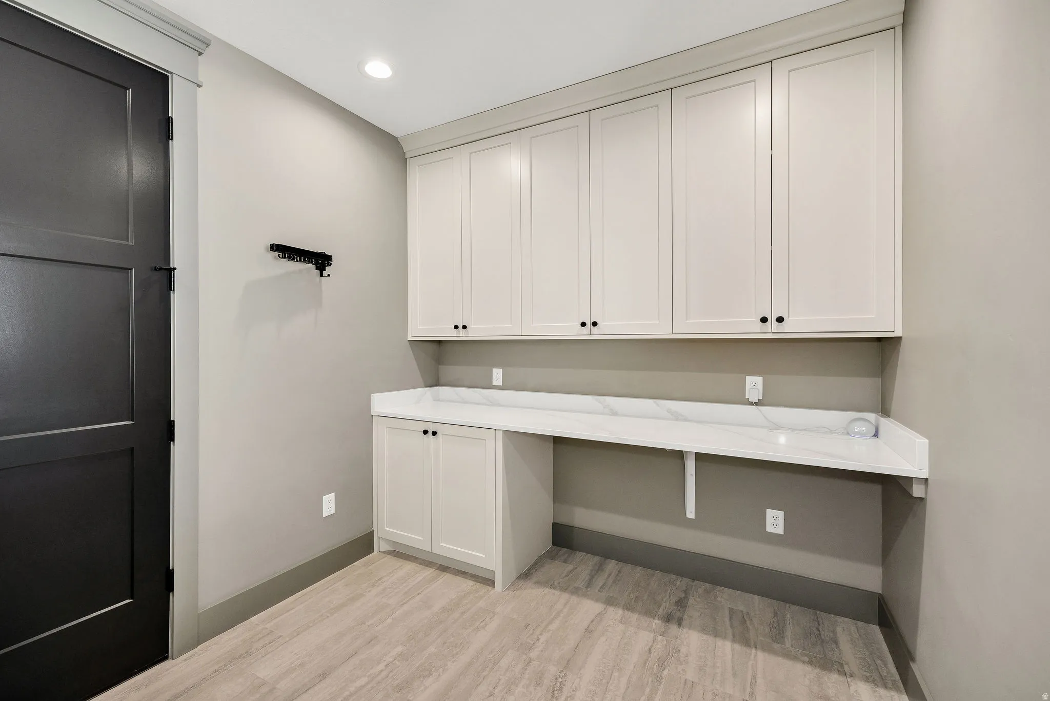 Custom cabinetry with integrated desk space, solid surface countertop, wood-finish flooring, and recessed lighting