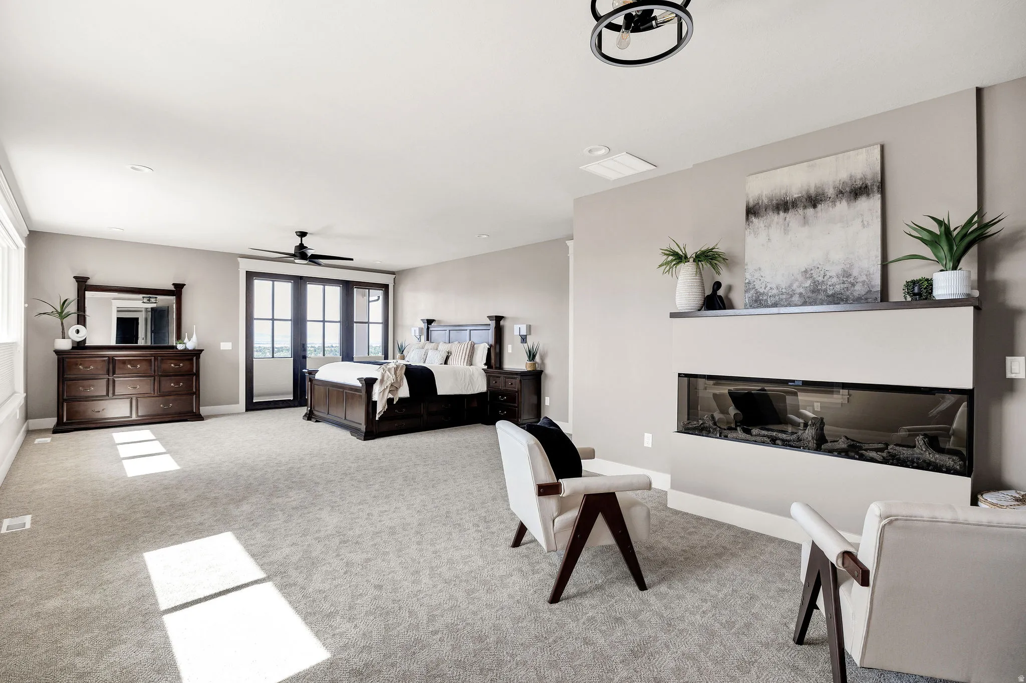 Spacious room featuring a linear fireplace, black framed glass double doors, light gray carpeting, and a ceiling fan