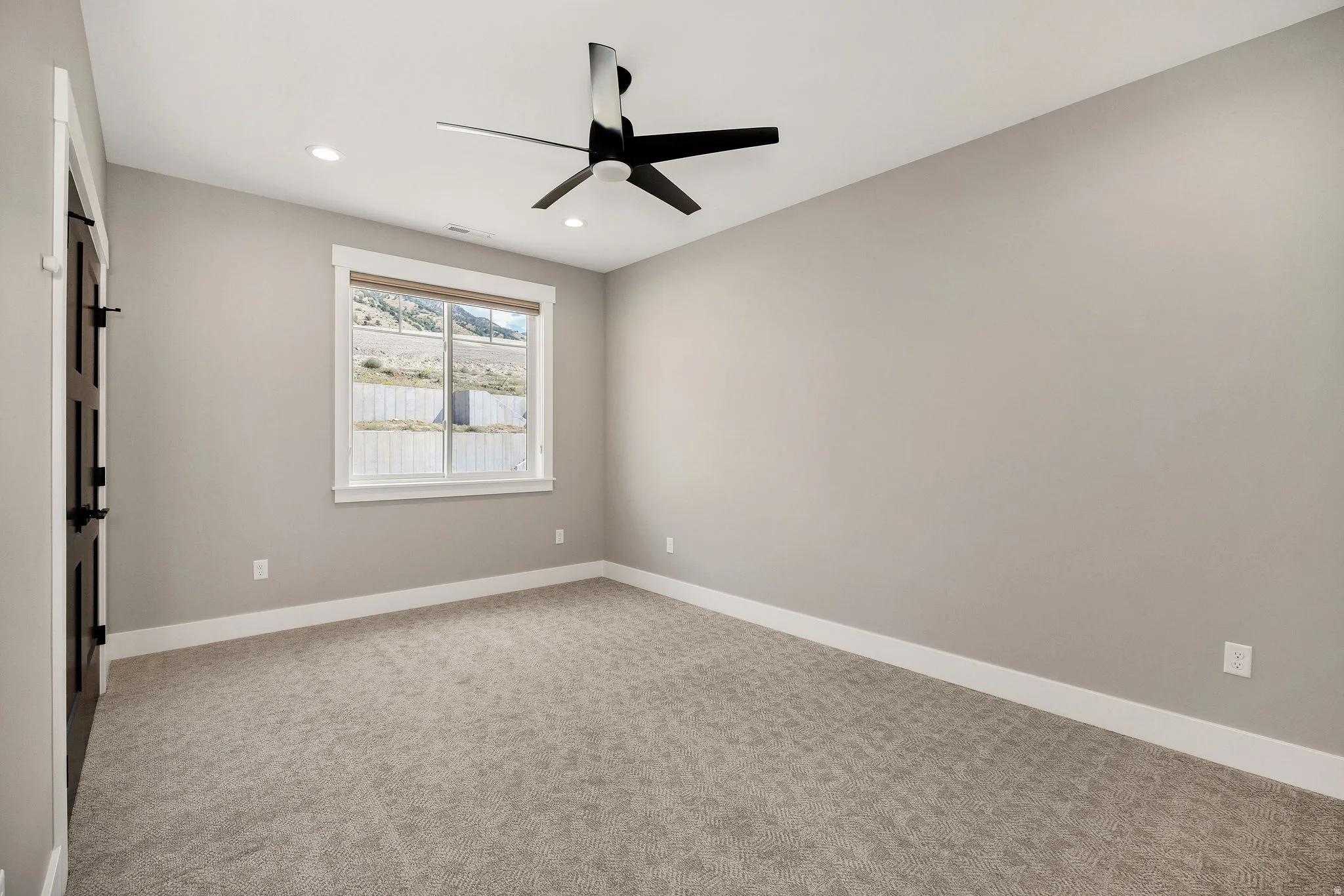 Recessed ceiling lighting, modern ceiling fan, neutral wall finishes, carpeted flooring, and a window with white trim