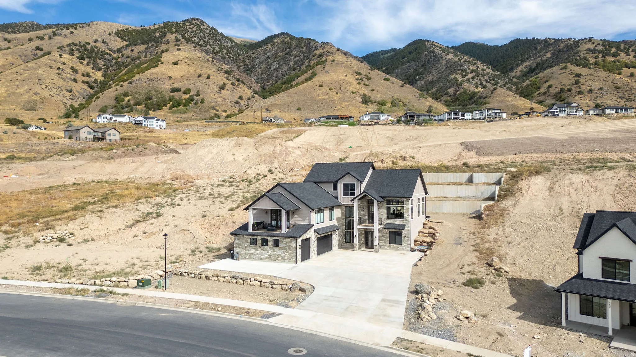 Contemporary home with a stone and stucco exterior, dark shingle roof, integrated garage, and a concrete driveway