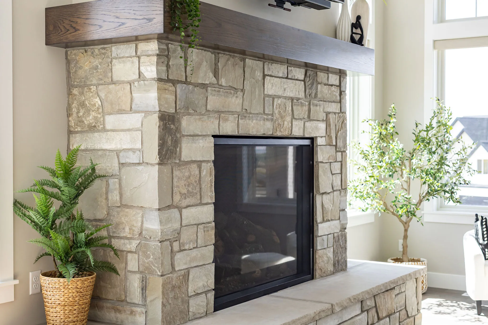 Stone fireplace with black metal surround and hearth, topped with a wood-finish mantel