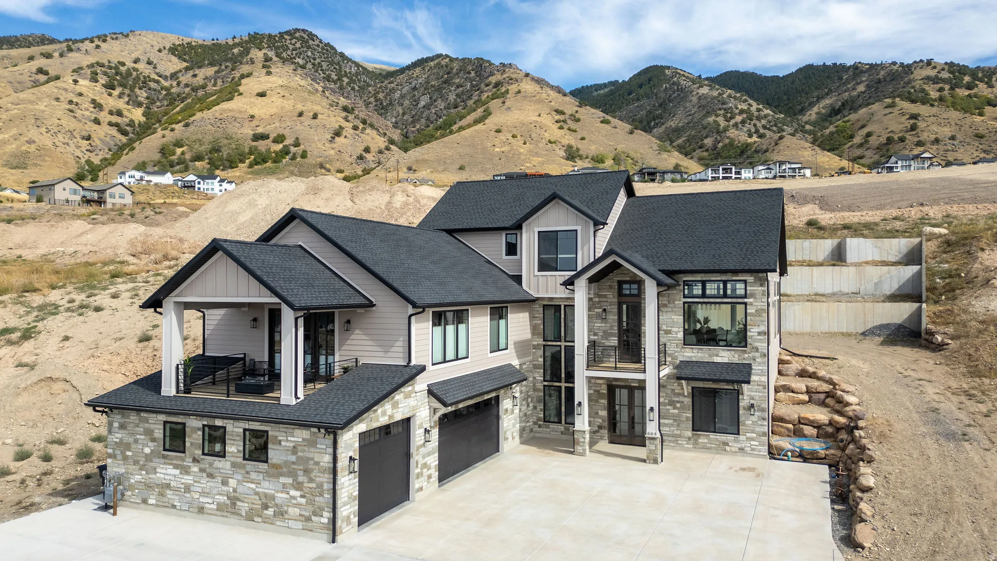 Contemporary residence featuring a multi-level design with stone and siding exterior, a covered balcony, and an attached 3-car garage