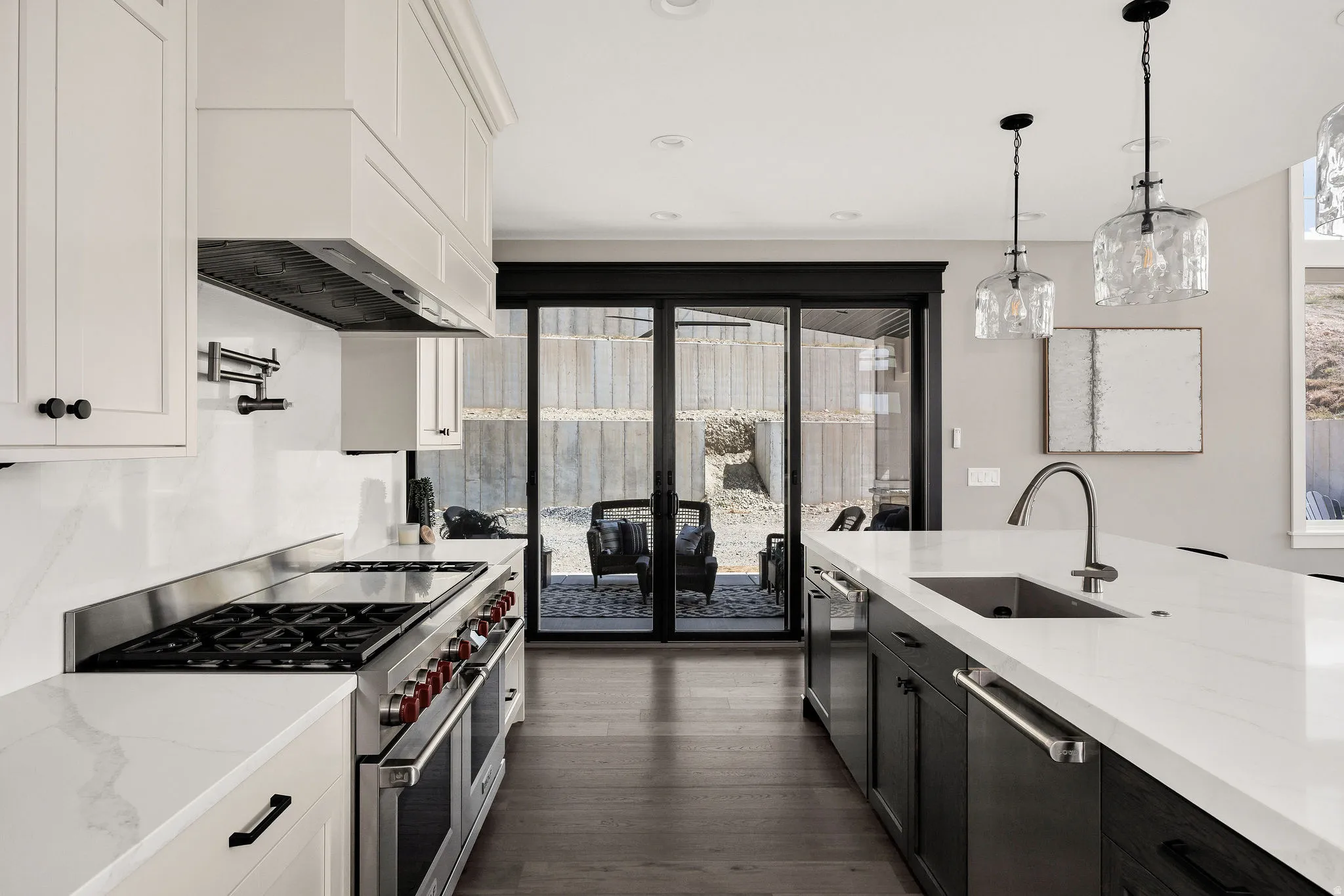 Gourmet kitchen featuring a stainless steel range, white shaker cabinetry, quartz countertops, and a pot filler