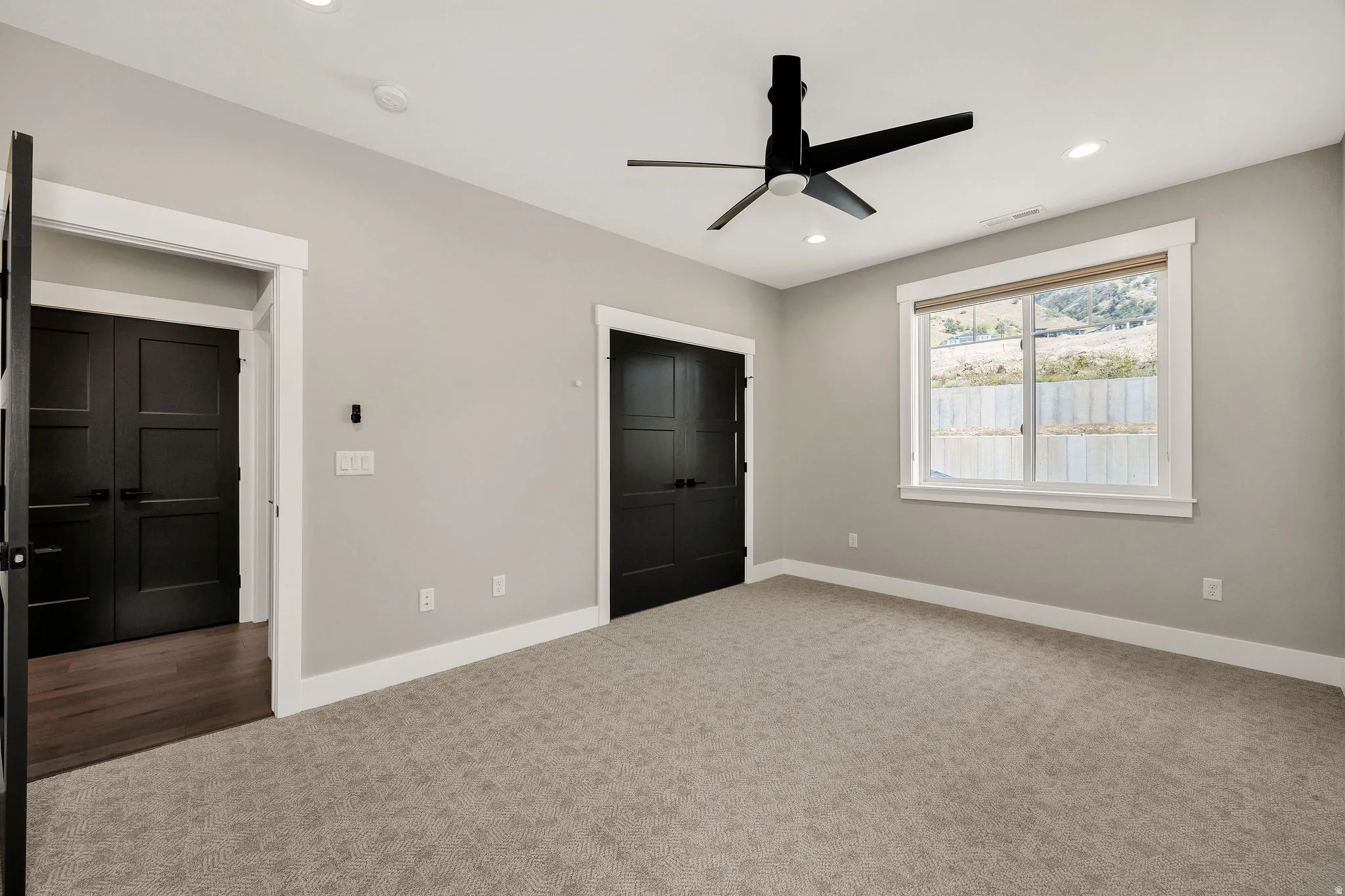 Carpeted room featuring a ceiling fan with light, recessed lighting, and a large window