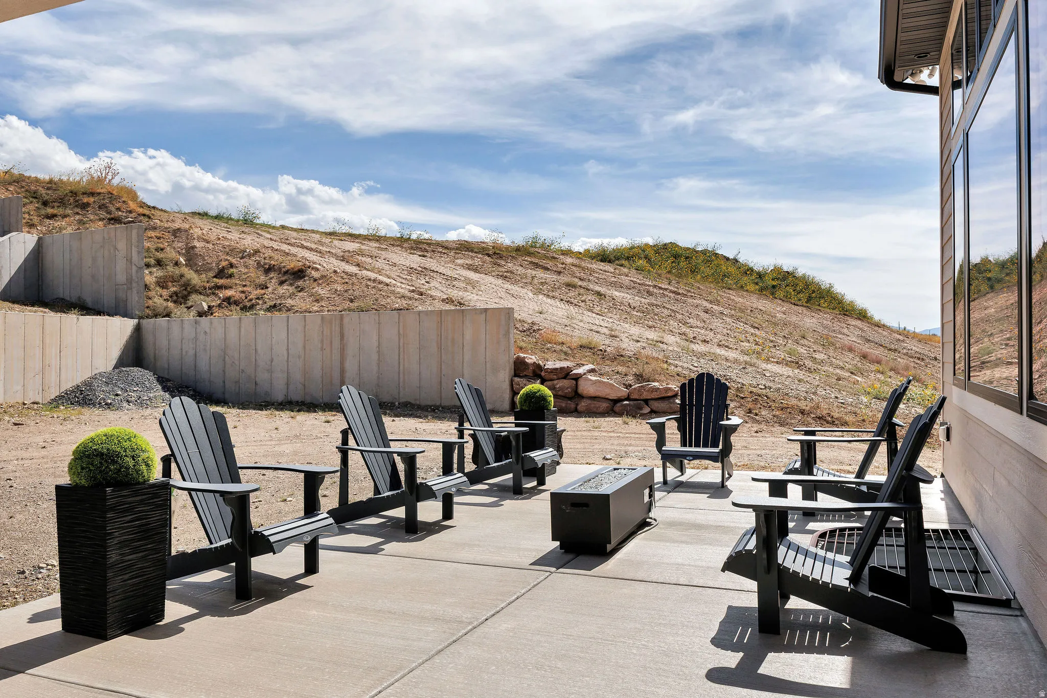 Concrete patio with a built-in outdoor fire pit and a tiered retaining wall