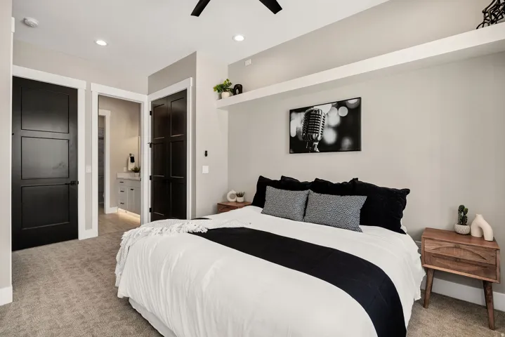 Recessed lighting, wood-finish bedside table, overhead ceiling fan, built-in shelving, carpet flooring