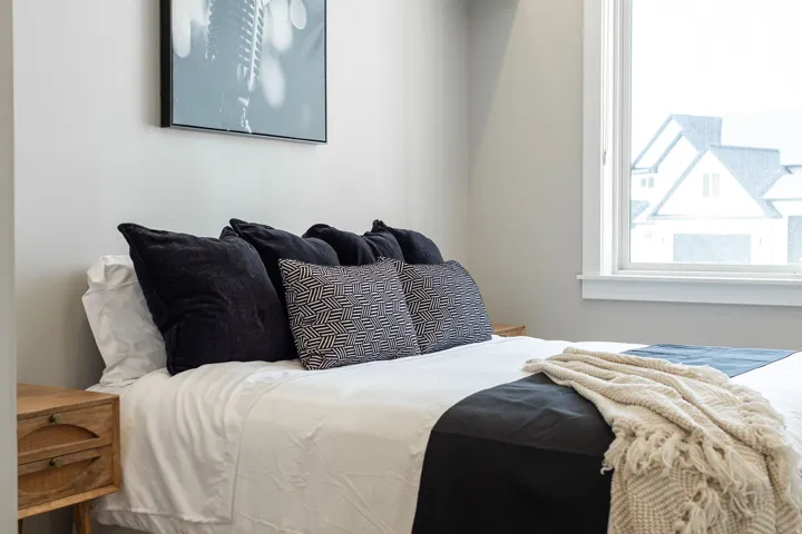 White window trim, light gray painted wall, and a wooden nightstand with two drawers