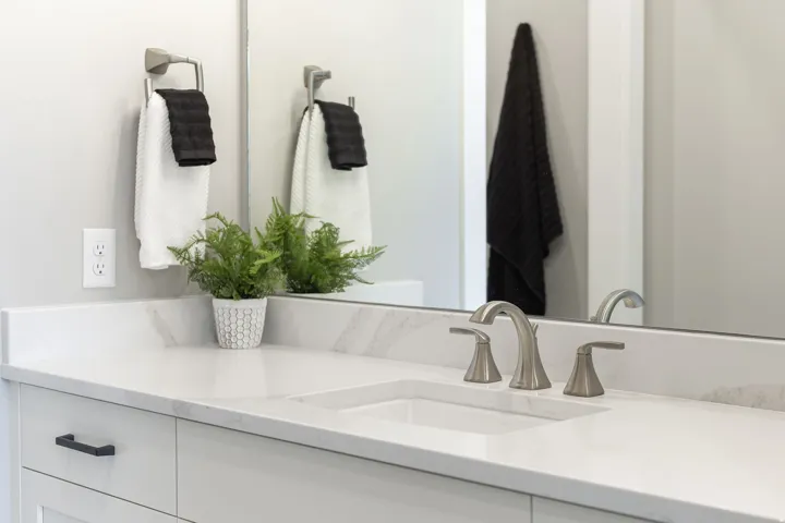 White vanity with integrated sink, brushed nickel faucet, and white countertop