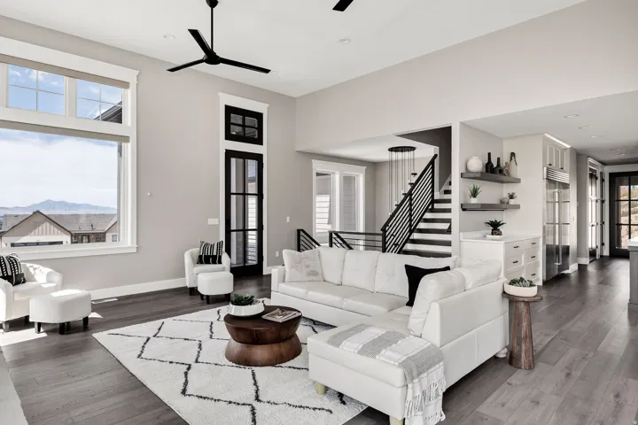 Open concept living area featuring high ceilings, wood-finish flooring, a modern staircase with metal railings, and integrated shelving with lower cabinetry