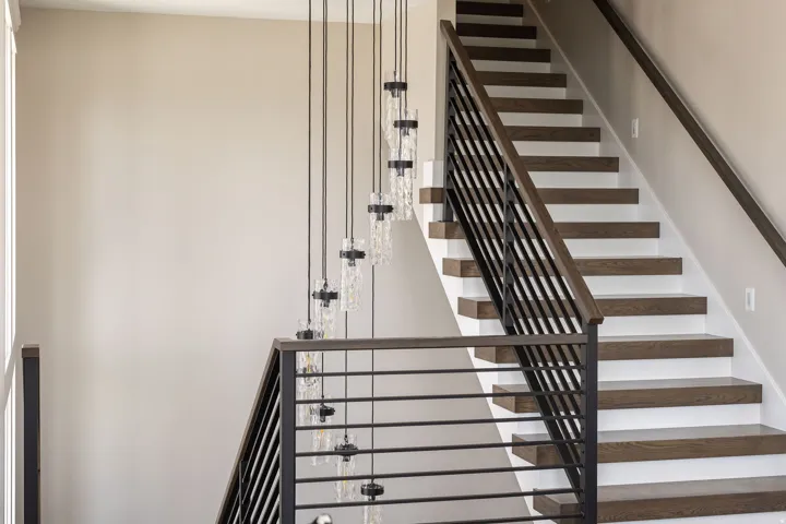 Staircase featuring wood treads, white risers, and a contemporary metal railing