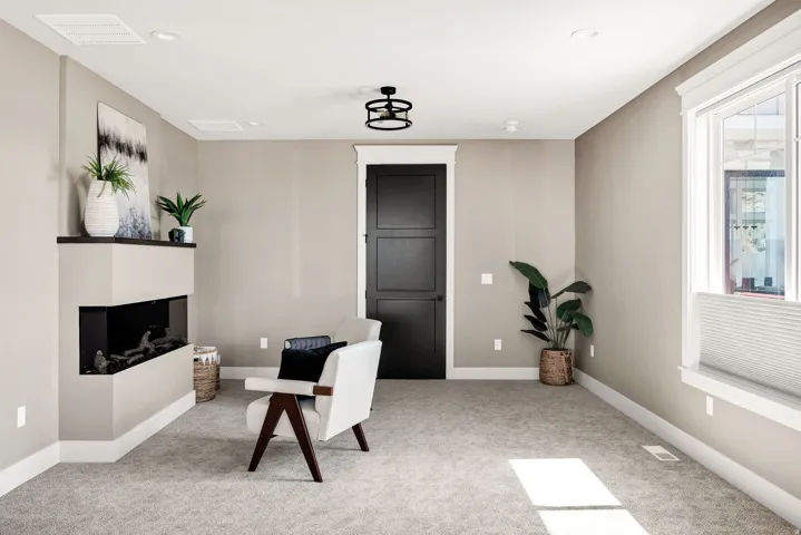 Corner fireplace with a dark mantel, recessed lighting, ceiling light fixture, white trim, and light-colored carpet