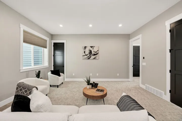 Recessed ceiling lighting, light gray wall paint, white trim, dark paneled doors, and light neutral carpet flooring