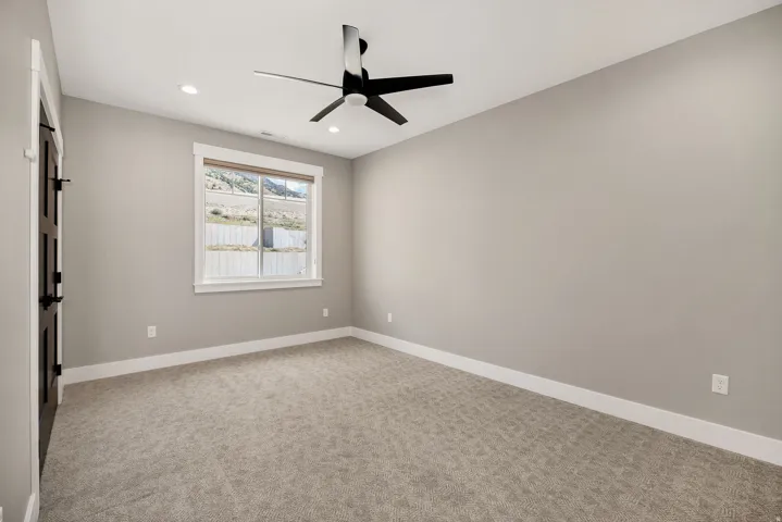 Recessed ceiling lighting, modern ceiling fan, neutral wall finishes, carpeted flooring, and a window with white trim