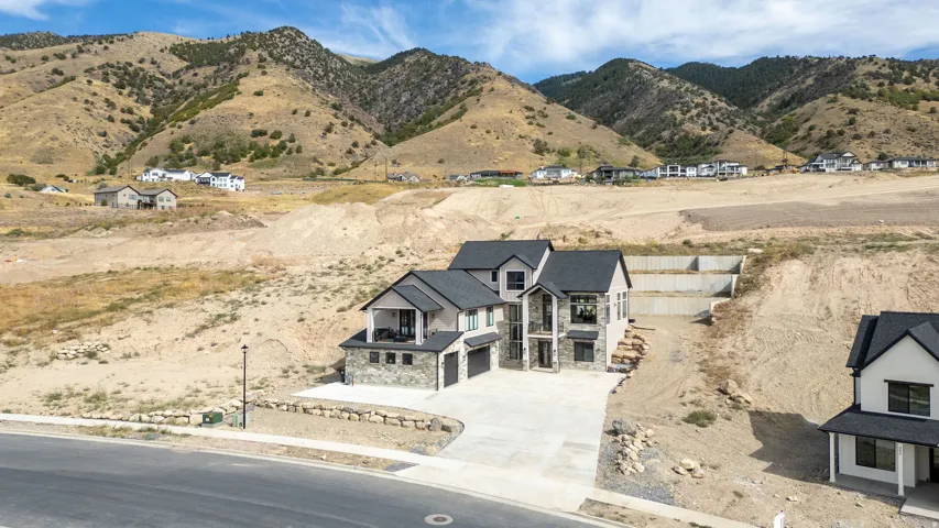 Contemporary home with a stone and stucco exterior, dark shingle roof, integrated garage, and a concrete driveway