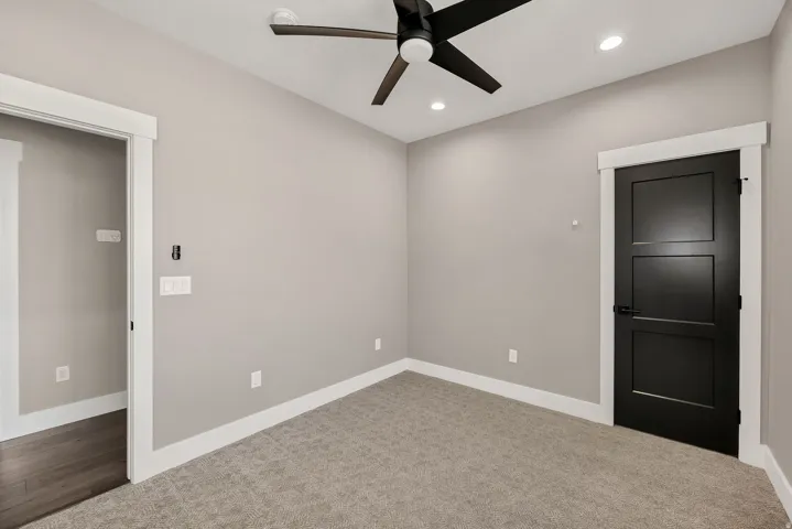 Recessed lighting, ceiling fan, dark panel door, and plush carpeting
