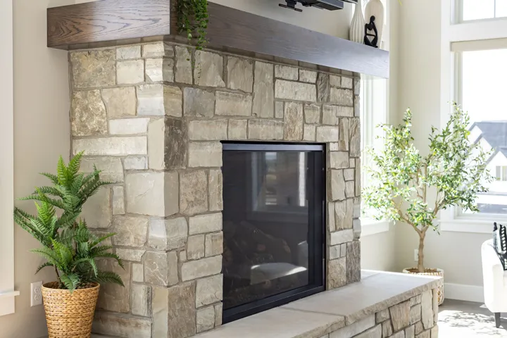 Stone fireplace with black metal surround and hearth, topped with a wood-finish mantel
