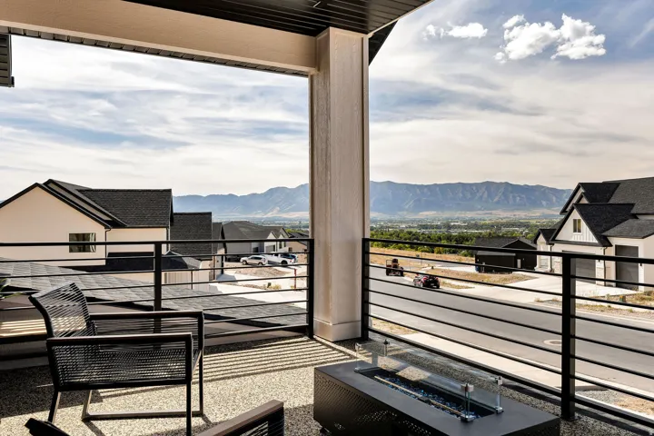 Covered balcony with a textured ceiling, black horizontal iron railing, and a durable aggregate surface