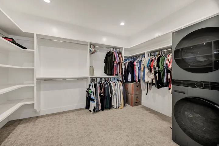 Integrated laundry appliances, built-in shelving, multiple hanging rods, recessed lighting, and soft carpet flooring
